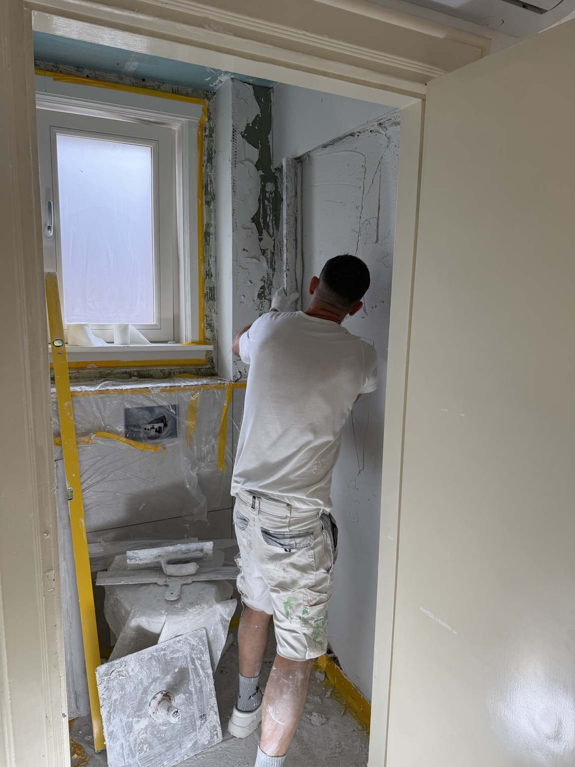 Stukadoor aan het werk bij een raam tijdens een renovatie