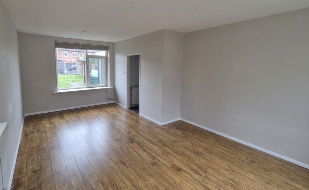 Recent opgeleverde woonkamer met strak afgewerkte wanden en houten vloer
